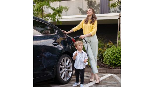 A smiling mother and her son charging their electric car
